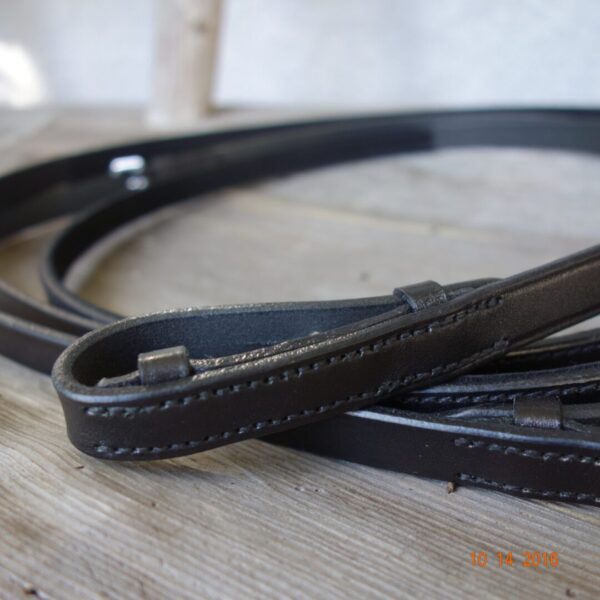 A black leather Albion Half Nubuck Competition Reins on a wooden table.