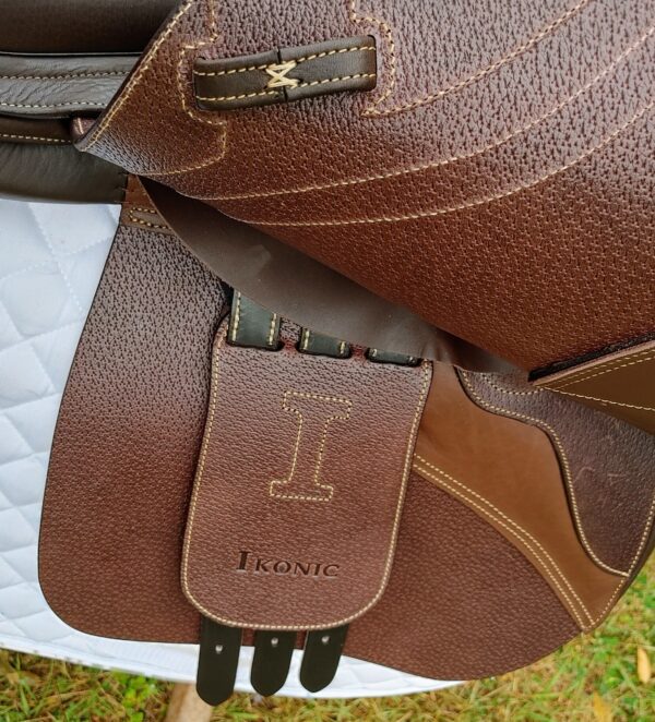 A brown Ikonic Jump "Evolution" - Calf Lined saddle with a brown leather strap.