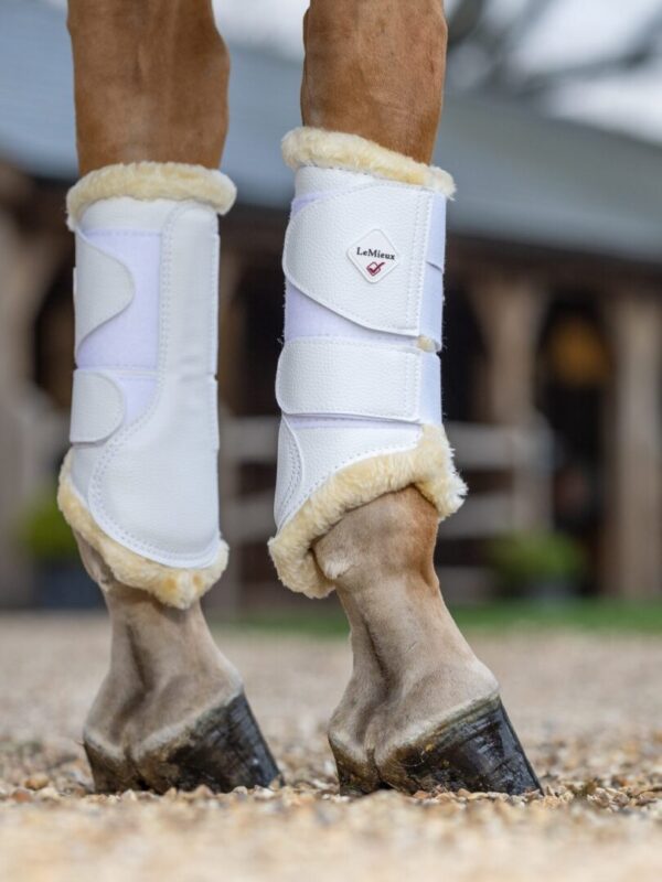 LeMieux Fleece Lined Brush Boots' feet standing on a gravel driveway.
