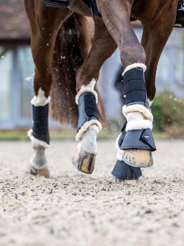 The feet of a brown horse are covered in LeMieux Fleece Lined Brush Boots.