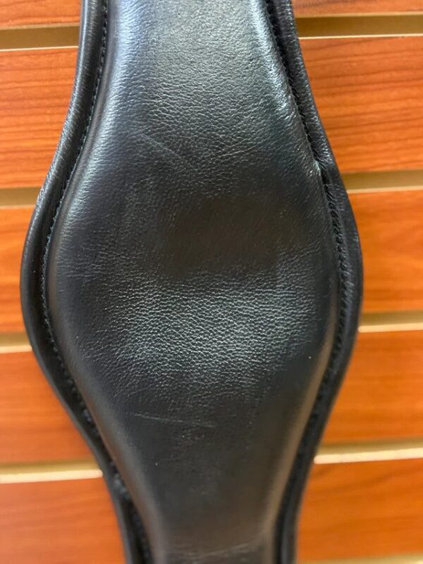 A close up of a Tota Sternum Relief Girth black leather saddle pad.