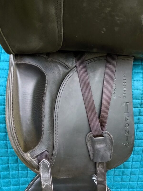 An IKONIC ‘PRO’ Evolution Dressage UC245 saddle with a strap attached to it.