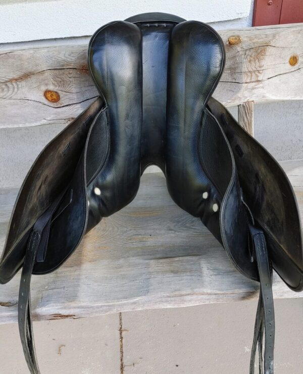 An Albion Platinum Genesis Dual Flap Dressage Saddle UC248 sitting on a wooden bench.