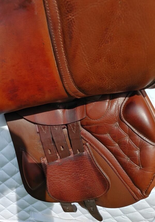 A Black Country Hunter/Jumper UC256 saddle on a white bed.