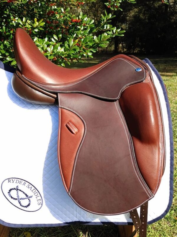 A brown and white Ryder Excellence Dressage R52 saddle sitting on a grassy area.