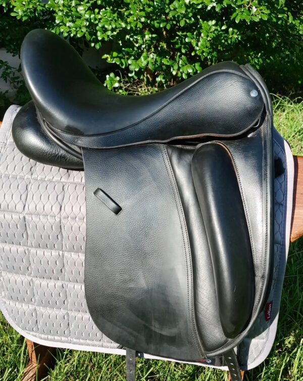 A black Custom Wolfgang Solo Dressage UC259 sitting on top of a saddle pad.