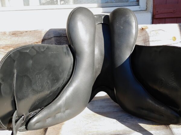 A pair of Ryder Excellence Monoflap Dressage - R11 saddles sitting on a wooden table.