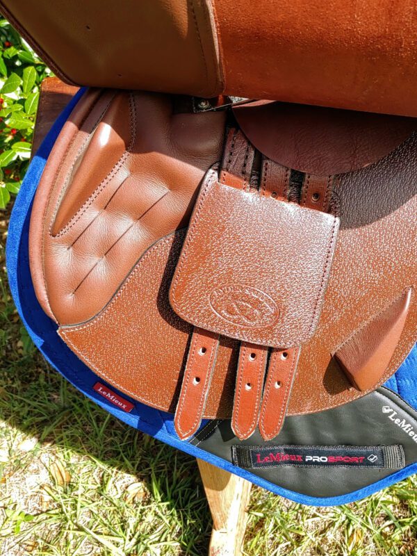 A brown DEMO - Ryder Riviera Dual Flap Jump - RY saddle with a blue saddle pad.