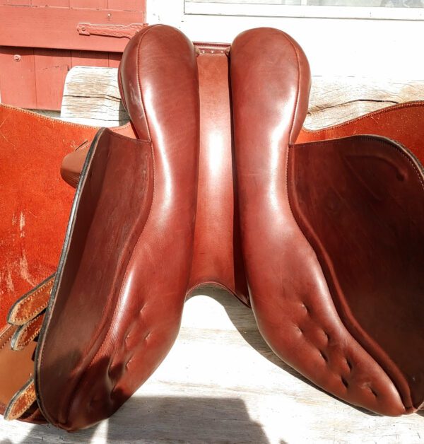 A pair of DEMO - Ryder Riviera Dual Flap Jump - RY saddles on a wooden bench.