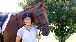 A woman is standing next to a brown horse at a schooling show at Flying Star Stables.