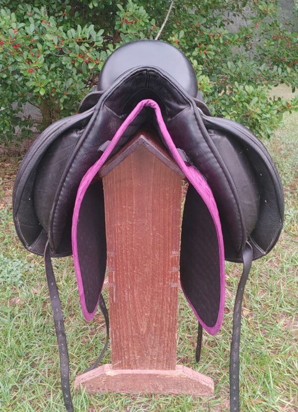 A black and purple Custom Revolution Dressage UC266 saddle on a wooden stand.