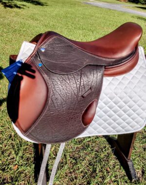 Textured brown jumping saddle on white pad