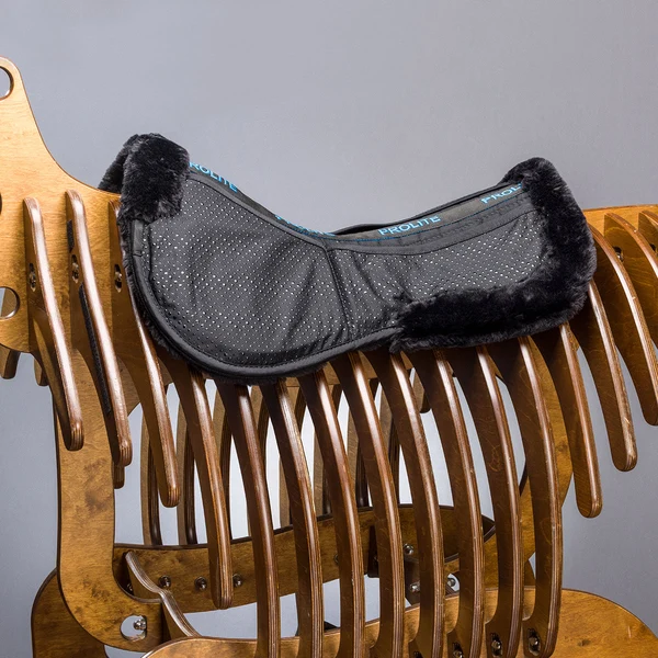Black sheepskin-trimmed saddle pad on wooden horse
