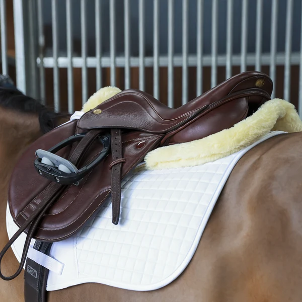 Brown leather saddle on horse with white pad
