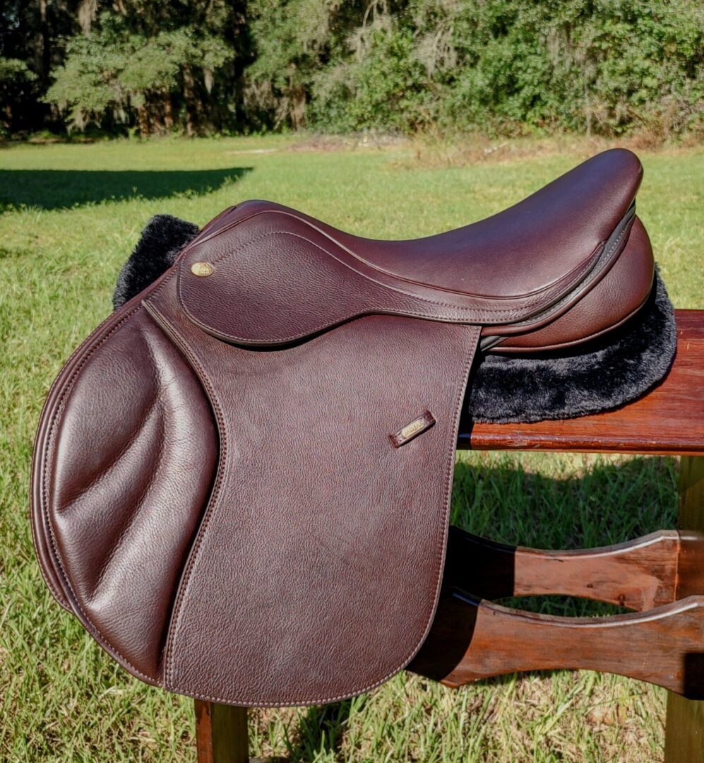 Rich brown saddle resting on wooden surface.