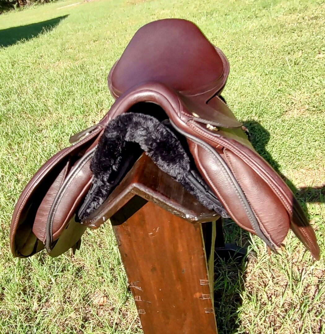 Brown saddle resting on wooden display stand.
